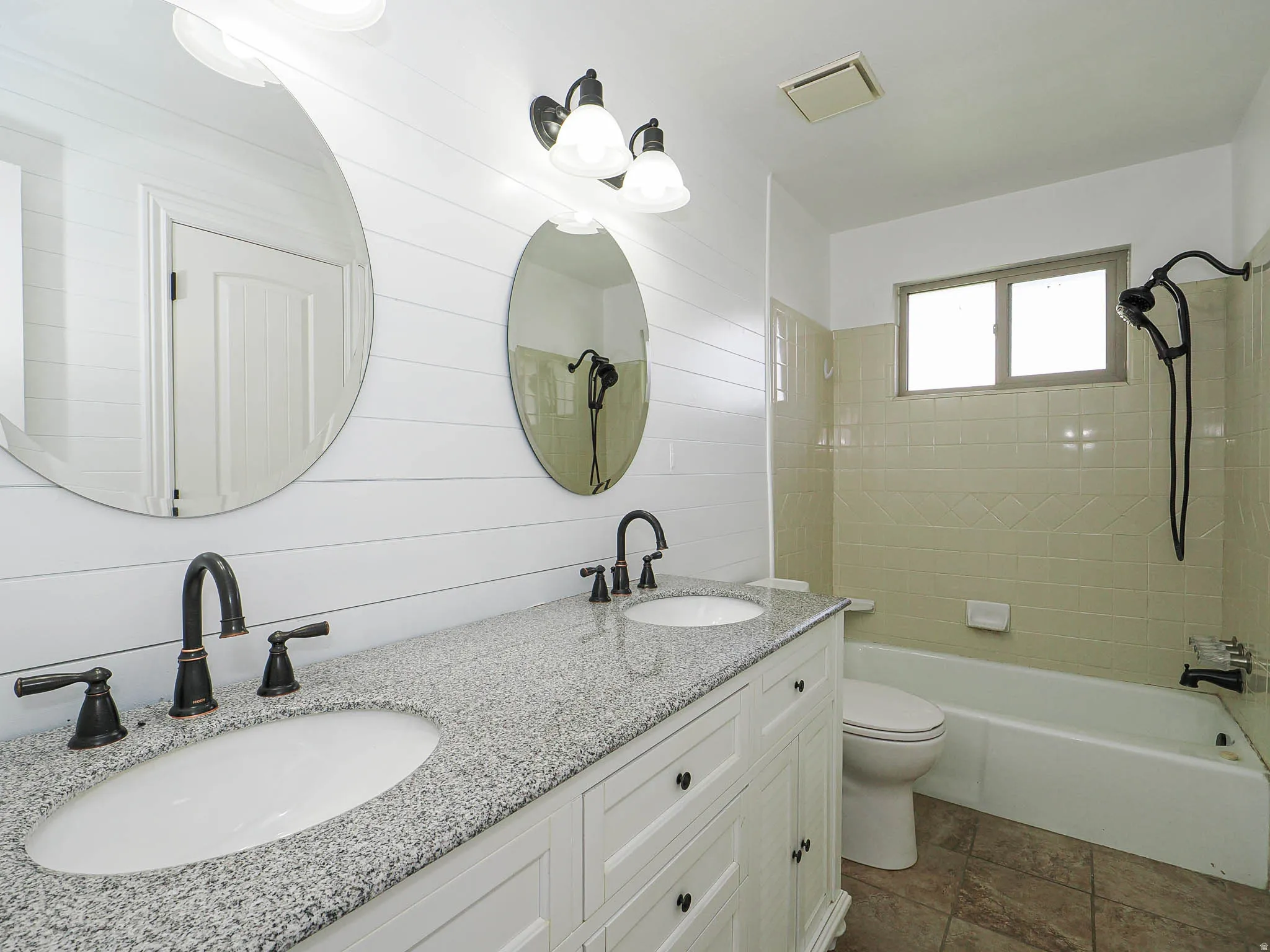 Bathroom featuring double vanity, bathtub / shower combination, and wood walls