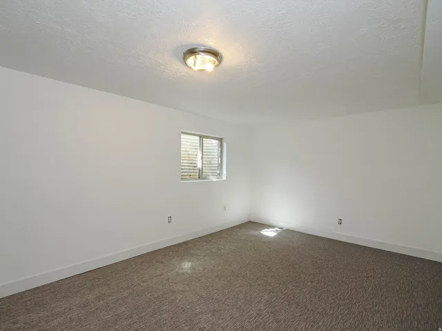 Unfurnished room featuring a textured ceiling and dark carpet