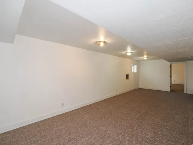 Finished basement featuring dark carpet and baseboards