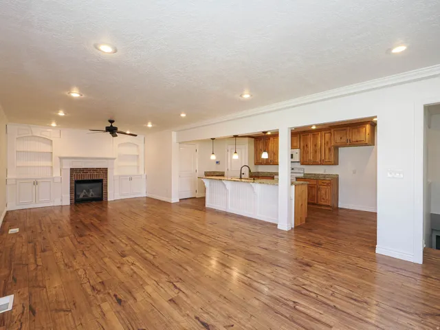 Unfurnished living room with a fireplace, dark wood-type flooring, ceiling fan, a textured ceiling, and built in features