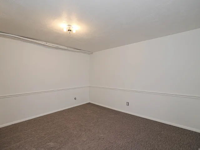 Empty room featuring dark carpet and a textured ceiling