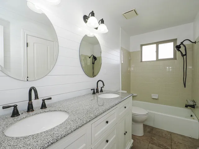 Bathroom featuring double vanity, bathtub / shower combination, and wood walls