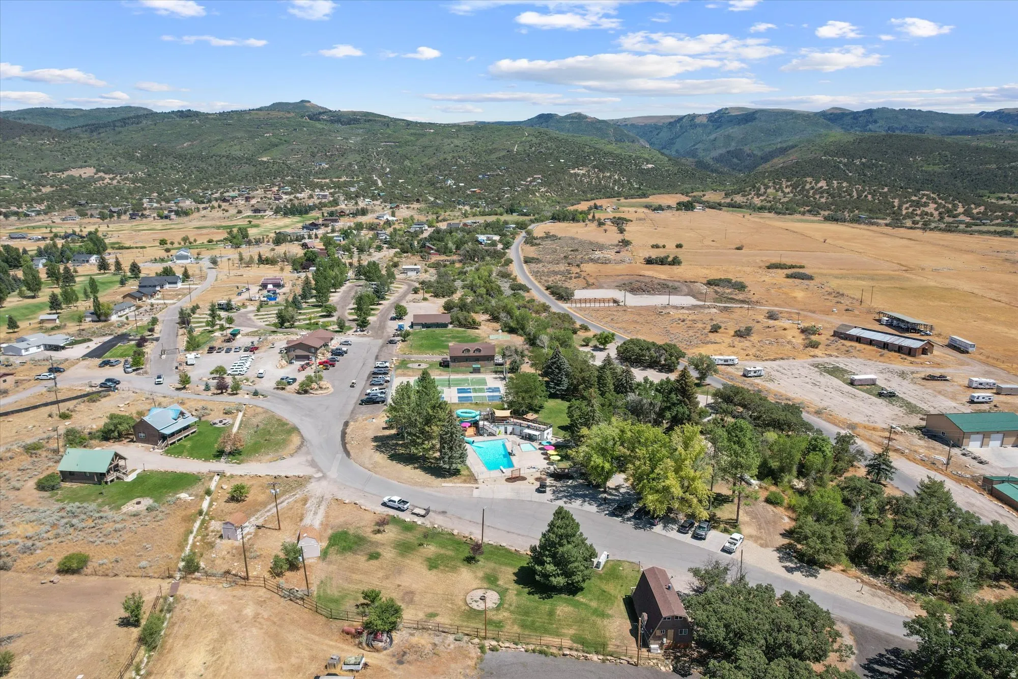 Aerial overview of property's location with a mountainous background and a pool area