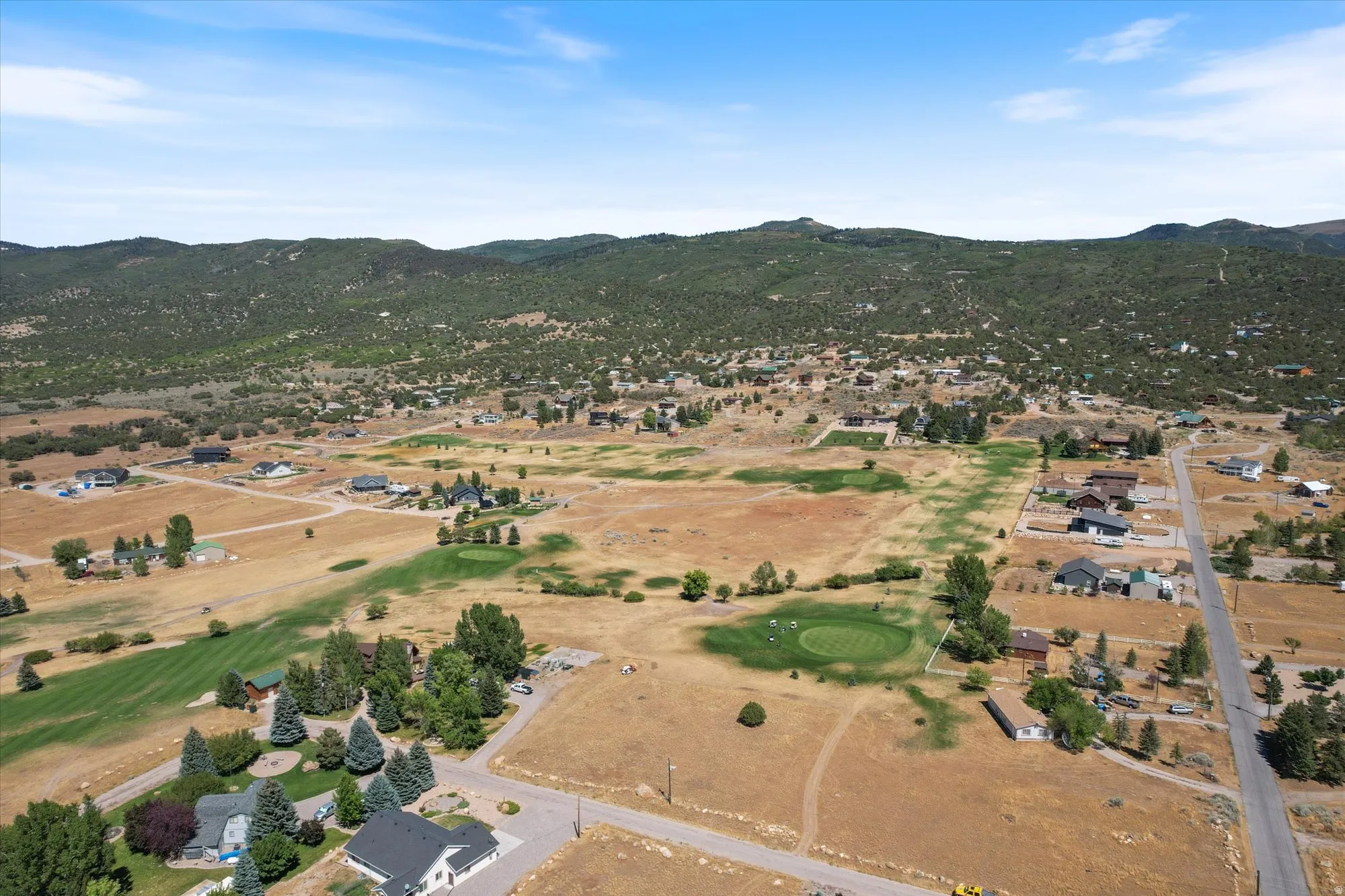 Aerial perspective of suburban area with a mountain backdrop and a golf club