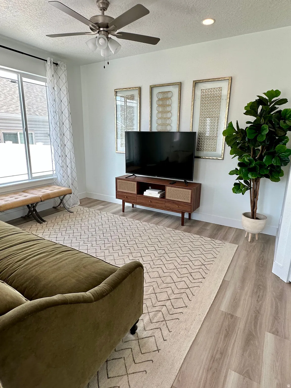 Living room with a textured ceiling, light wood-type flooring, and a ceiling fanPhotos of Dixon Model Home for reference only. Finishes may vary from photos shown.