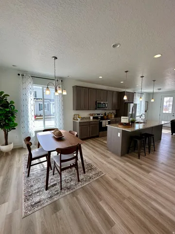 Dining space featuring light wood-style floors, suspended lighting, and a textured ceilingPhotos of Dixon Model Home for reference only. Finishes may vary from photos shown.