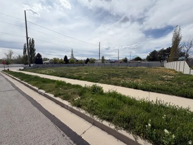 View of asphalt road featuring sidewalks, traffic signs, and curbs