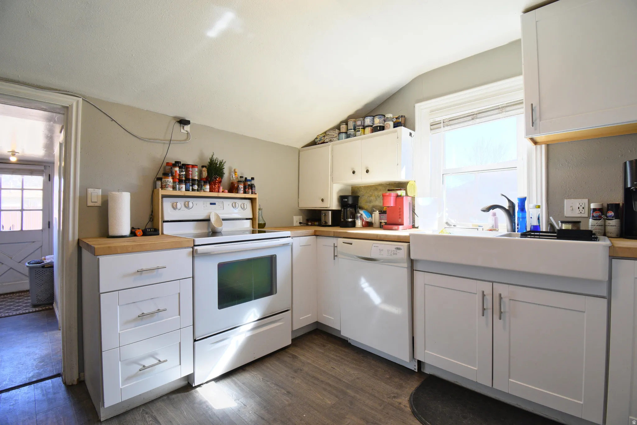Kitchen with white cabinetry, white appliances, dark wood-style flooring, lofted ceiling, and butcher block counters