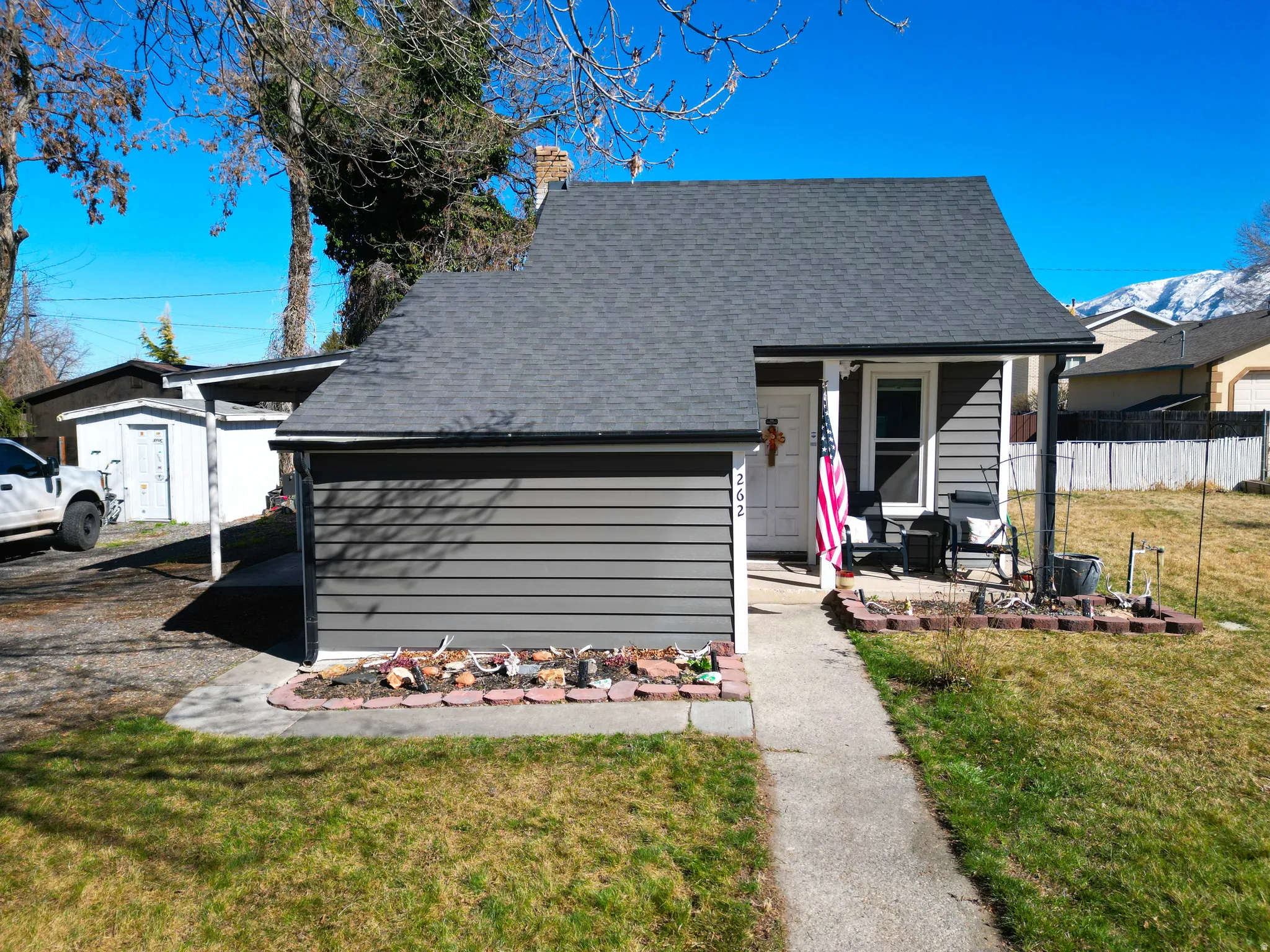 View of front of home featuring a front yard, a shingled roof, a porch, and a mountain view