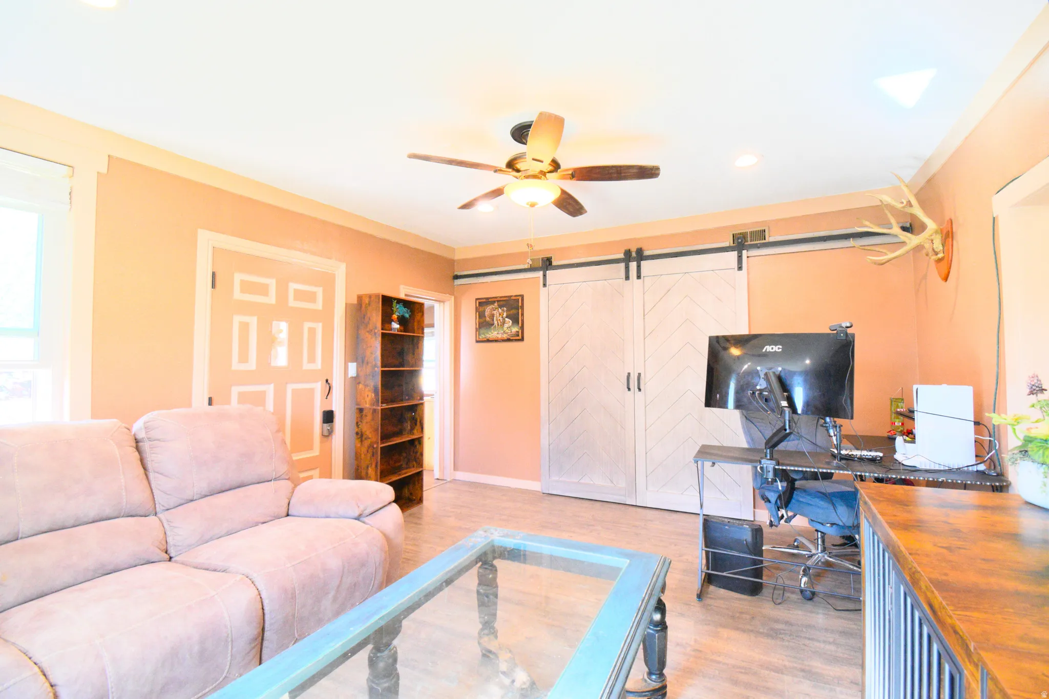 Living area with a barn door, light wood finished floors, ceiling fan, a desk, and recessed lighting