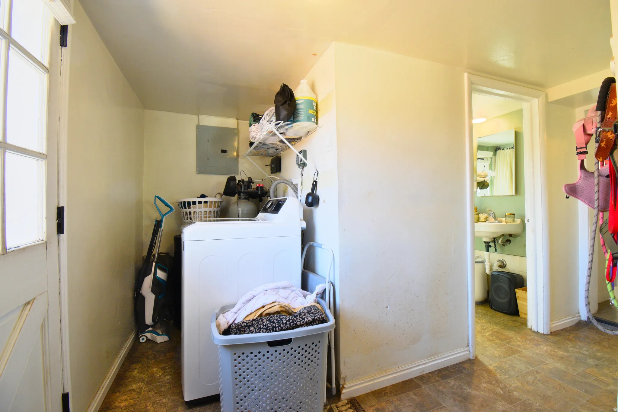 Laundry room featuring electric panel and stone finish flooring