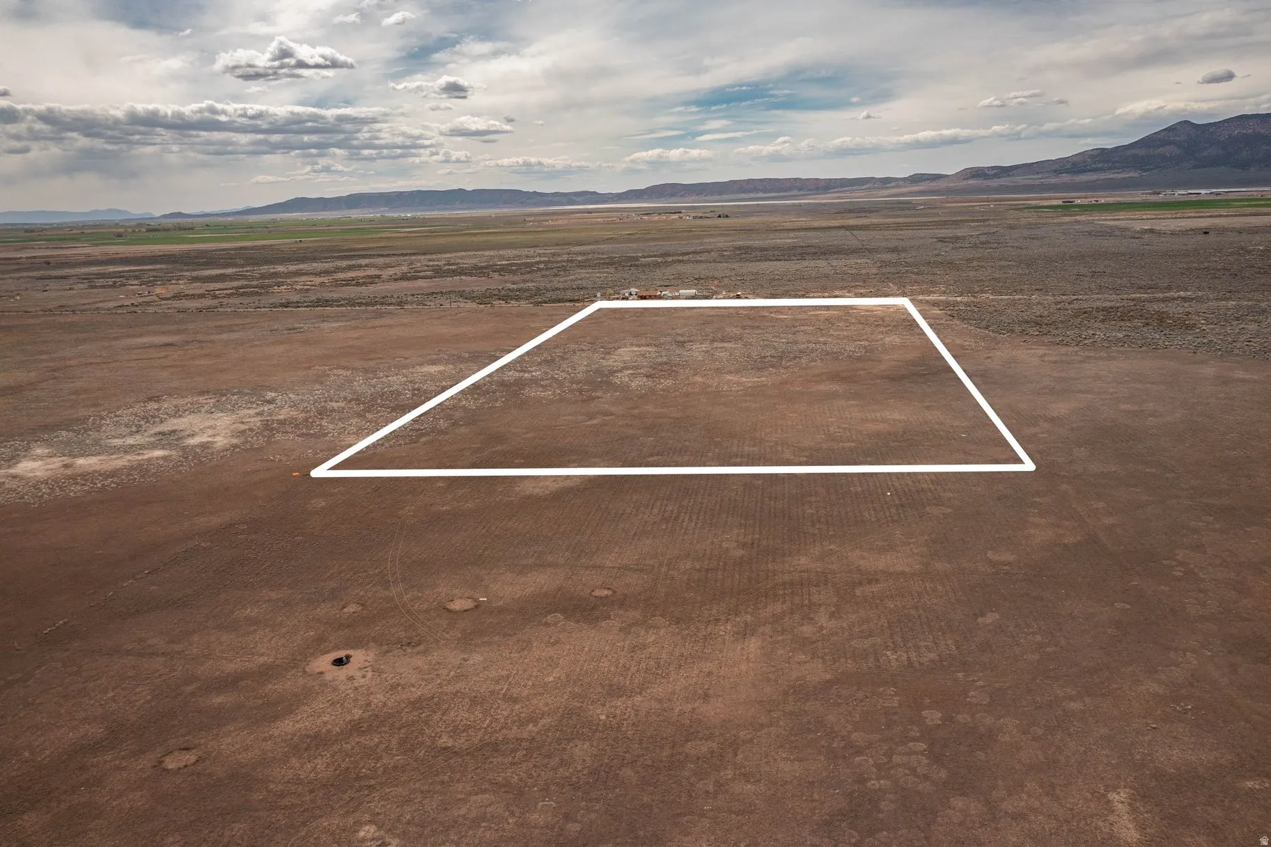 Aerial view of sparsely populated area with a mountain backdrop and property parcel outlined