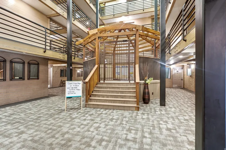 Stairs with a high ceiling, carpet floors, and brick wall