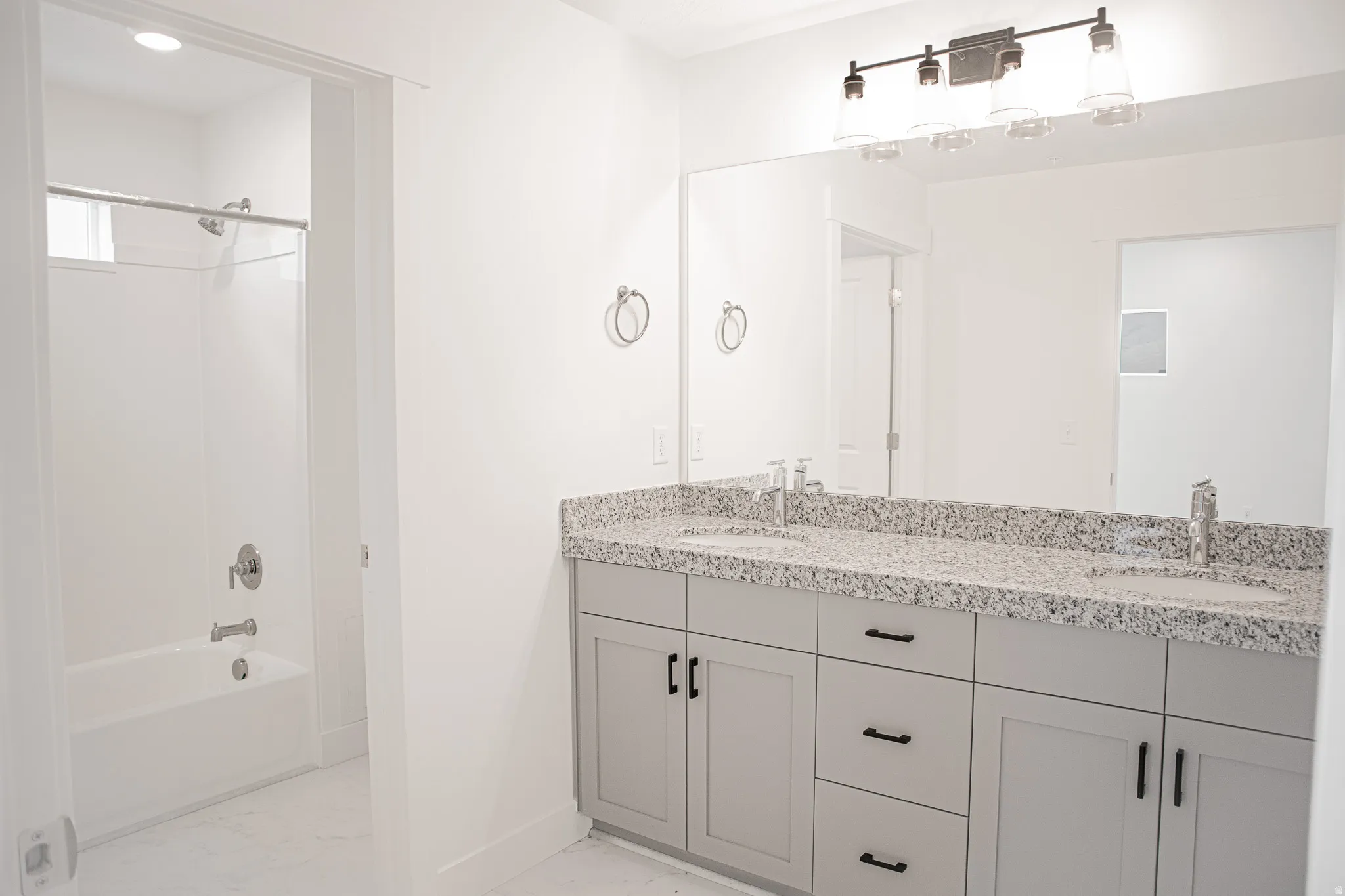 Primary bathroom with dual sinks, painted wood cabinets and granite slab countertops.