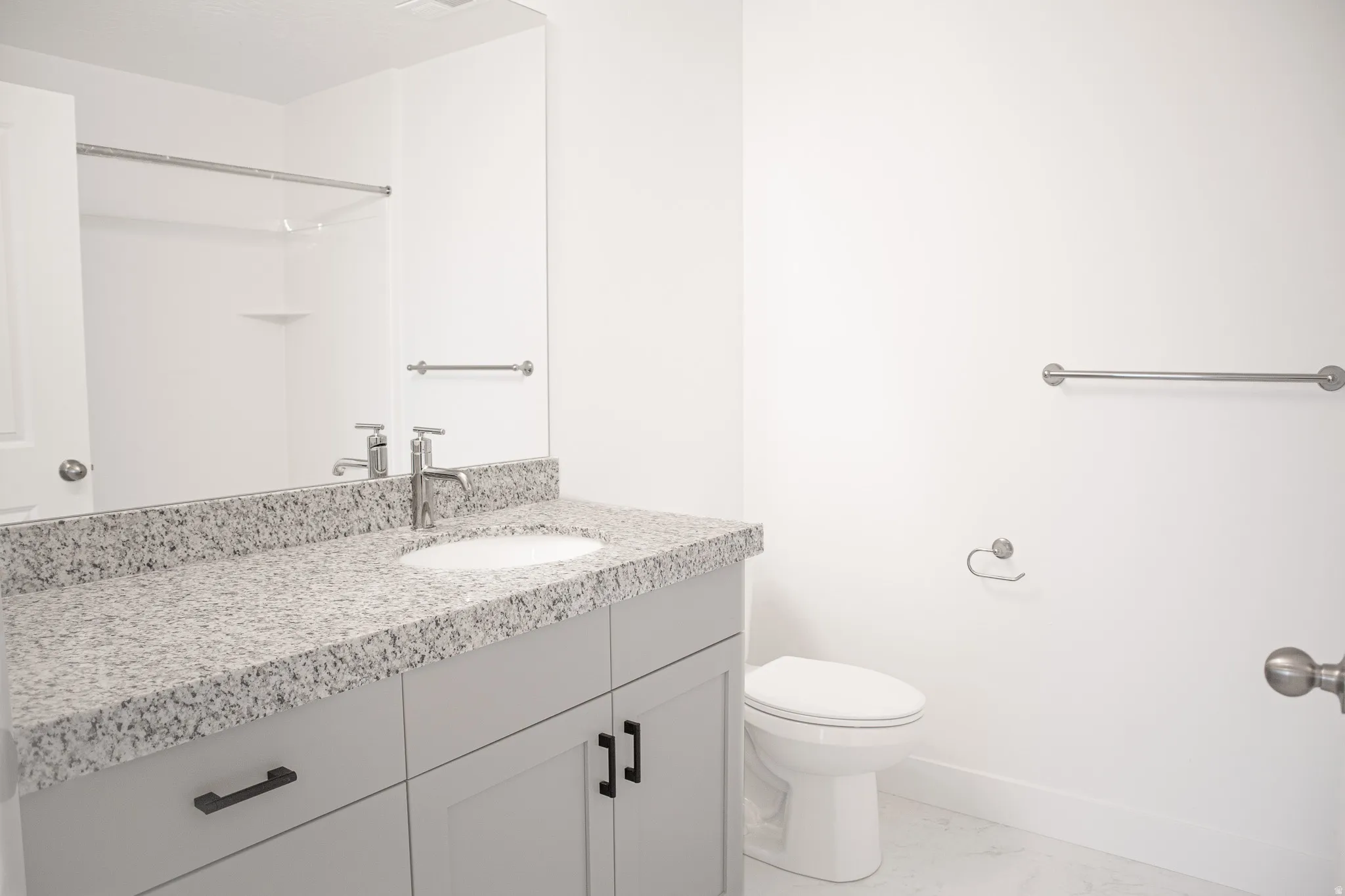 Full secondary bathroom with painted wood cabinets and granite slab countertops.