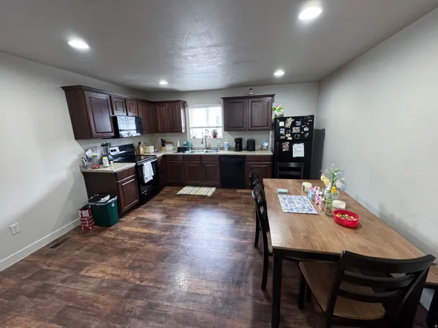 Kitchen with dark wood finish cabinets, light countertops, black appliances, recessed lighting, and dark wood-type flooring