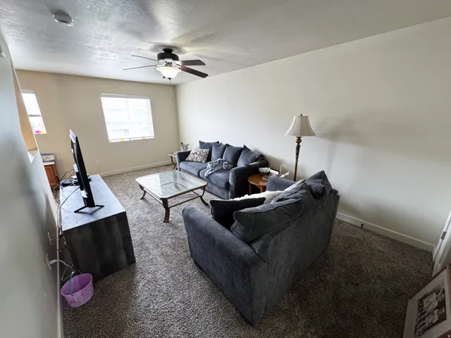 Living area with carpet flooring, ceiling fan, and a textured ceiling