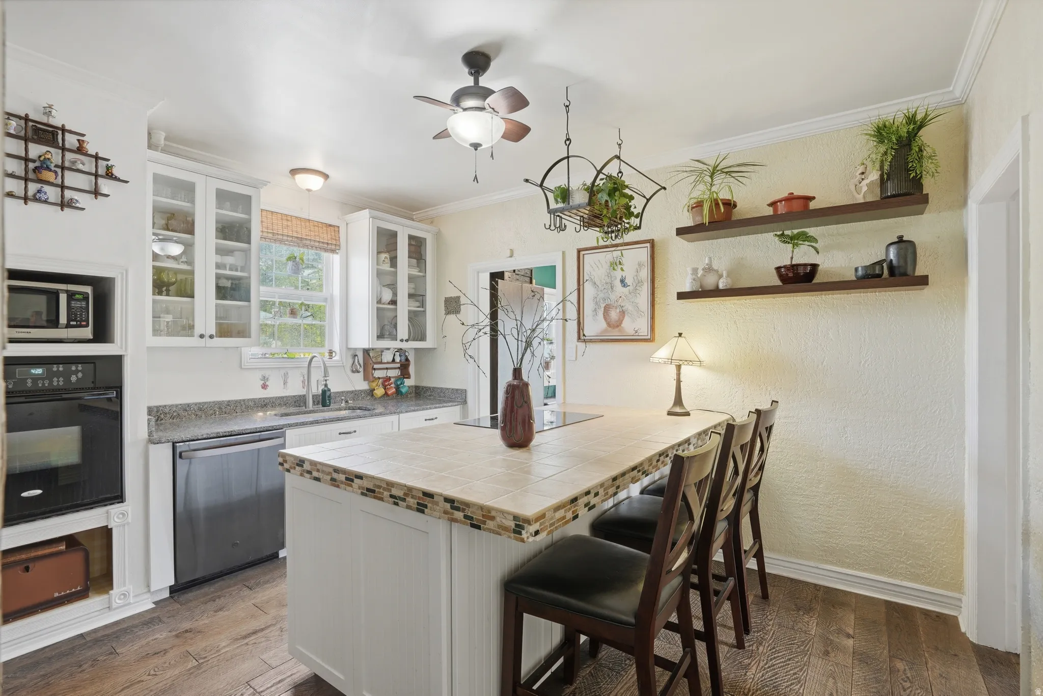 Kitchen featuring white cabinets, tile counters, stainless steel appliances, dark wood-type flooring, and ornamental molding