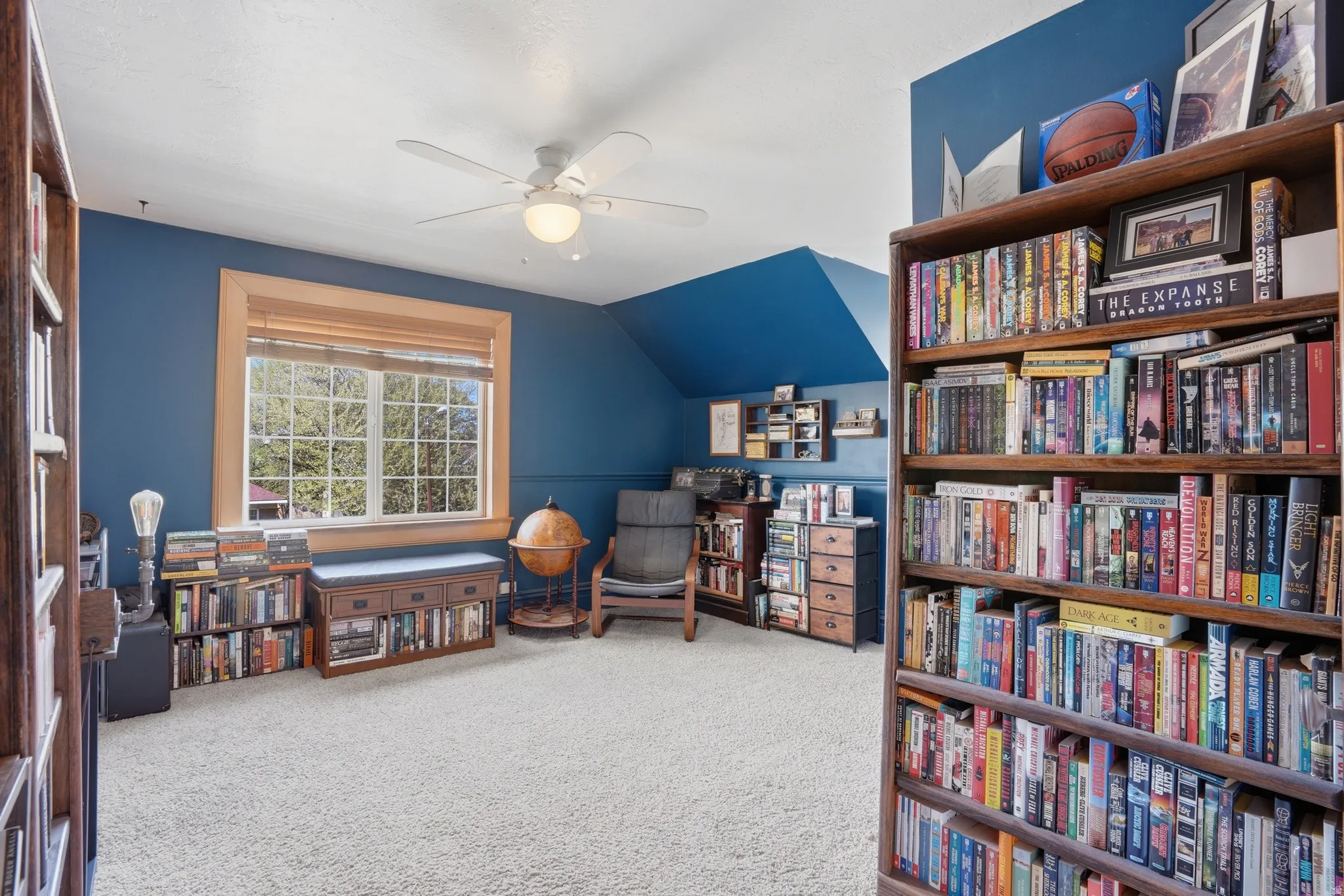 Living area featuring ceiling fan, light colored carpet, and vaulted ceiling