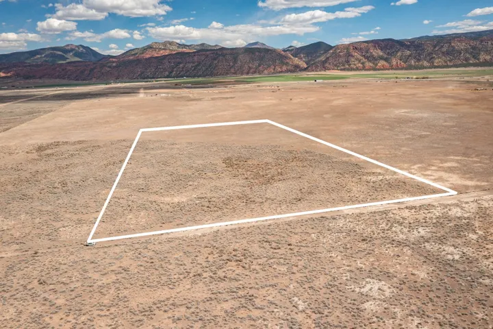 Aerial view of sparsely populated area featuring a mountainous background and property parcel outlined