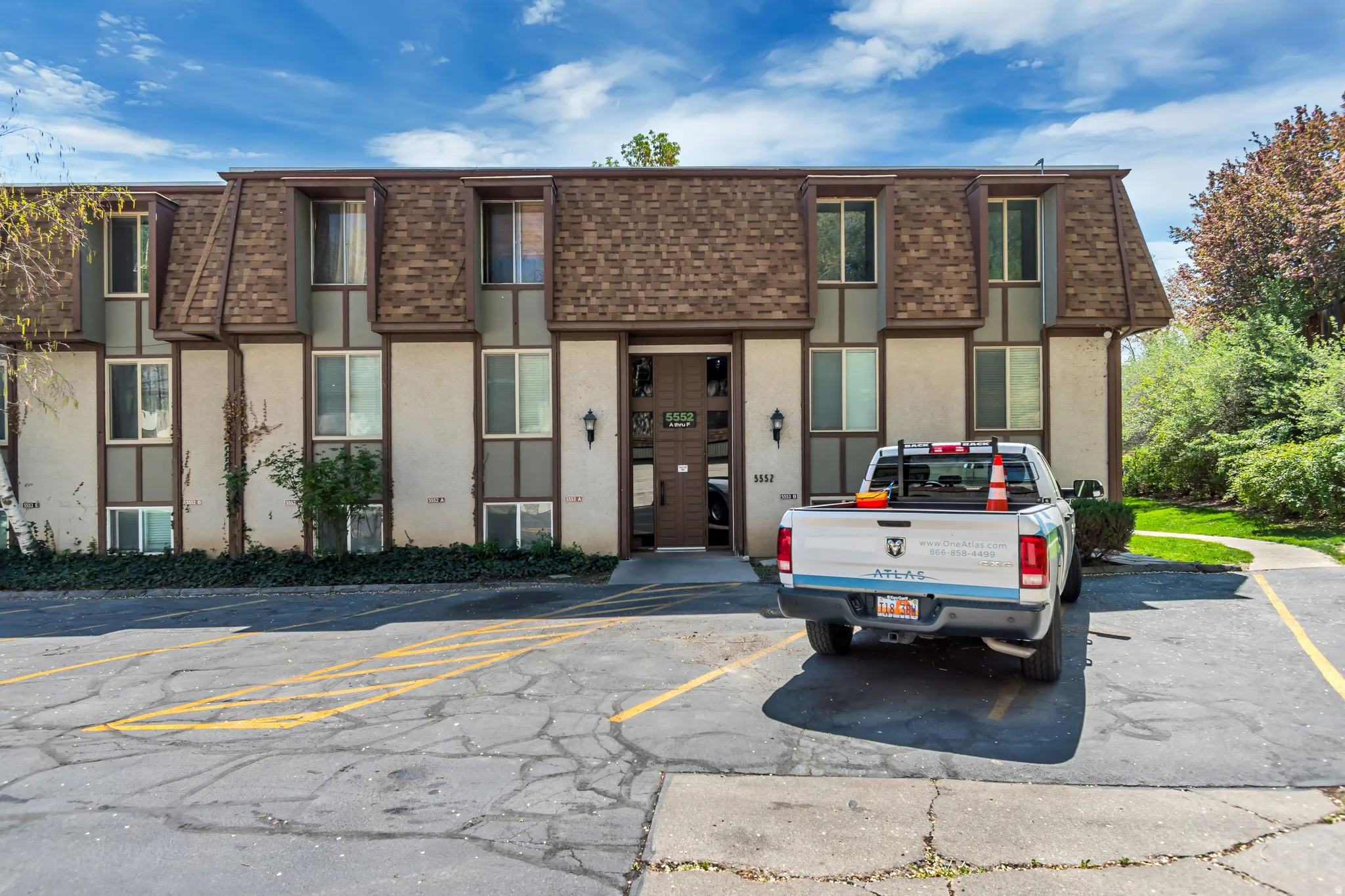 View of front of property featuring stucco siding, mansard roof, a shingled roof, and uncovered parking