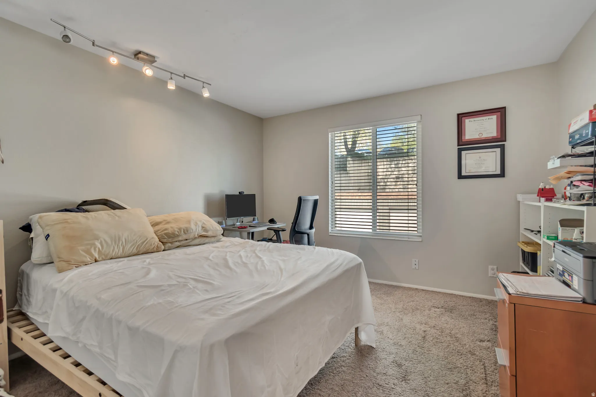 Bedroom featuring light carpet and track lighting