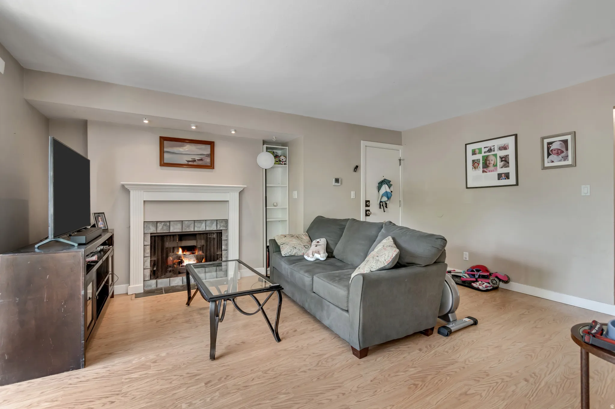 Living room with light wood-type flooring and a tiled fireplace