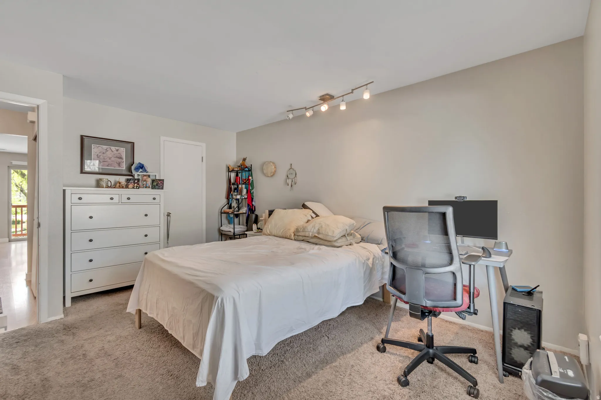 Bedroom featuring light carpet, an office area, and track lighting