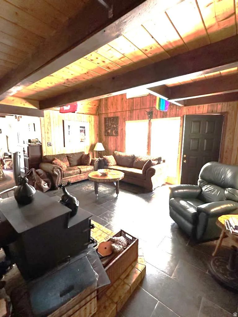 Living room with wood walls, lofted ceiling with beams, and wood ceiling