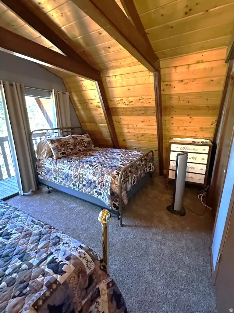 Carpeted bedroom featuring vaulted ceiling with beams, wooden ceiling, and wood walls