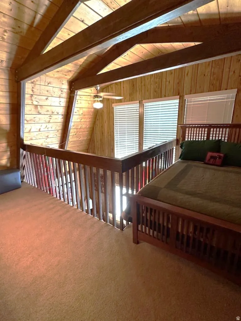 Carpeted bedroom featuring wooden walls, wooden ceiling, and lofted ceiling with beams