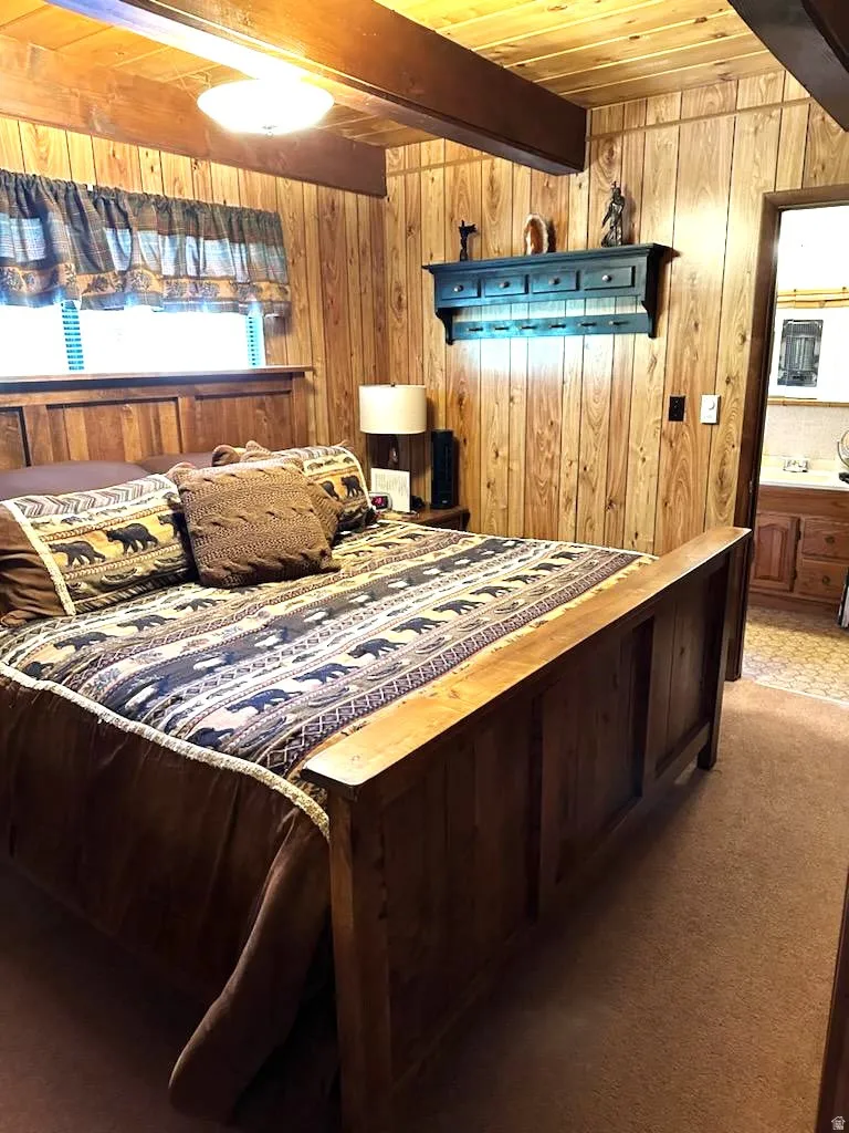 Carpeted bedroom with wood walls and a wood ceiling with exposed beams