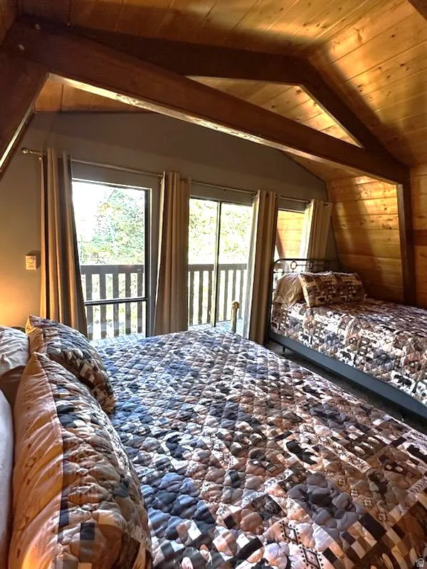 Bedroom with access to exterior, a wood ceiling with exposed beams, multiple windows, and wood walls