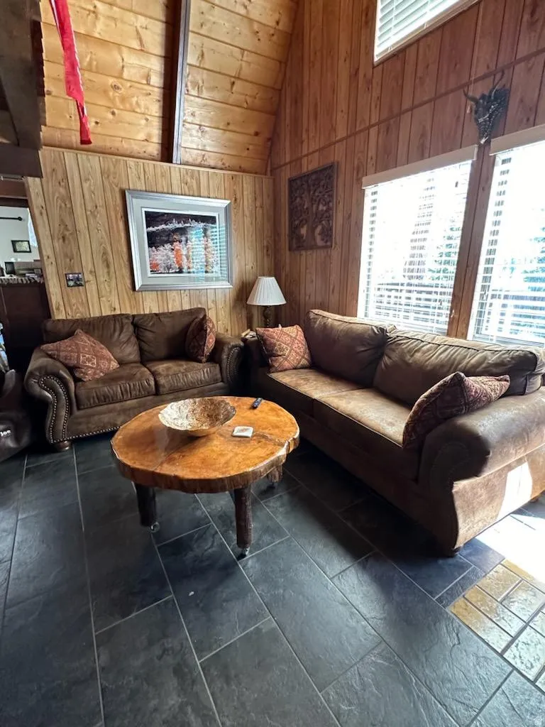 Living area with wooden walls and a high wood beamed ceiling