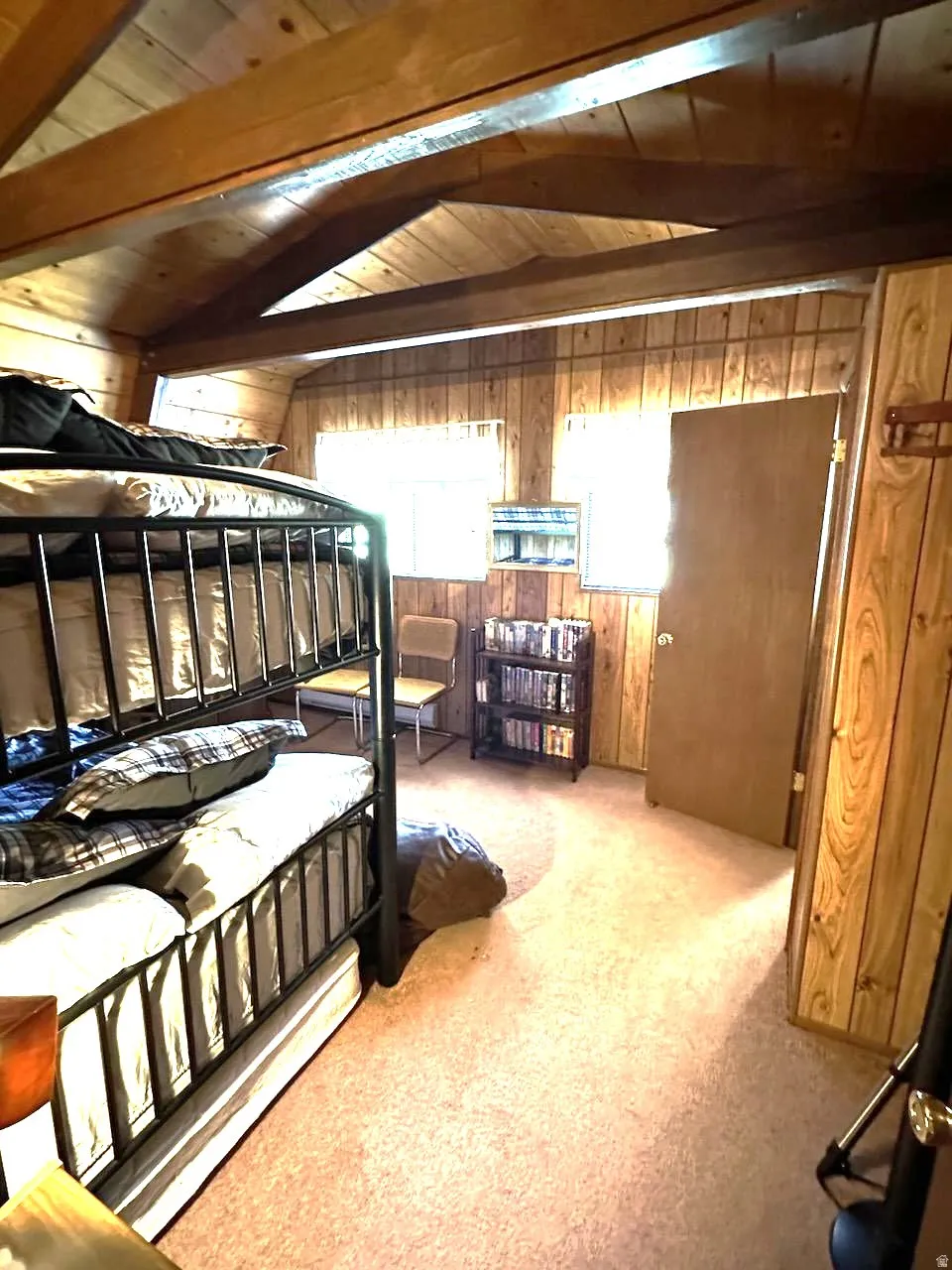 Bedroom featuring wood walls, light colored carpet, and a wooden ceiling with exposed beams
