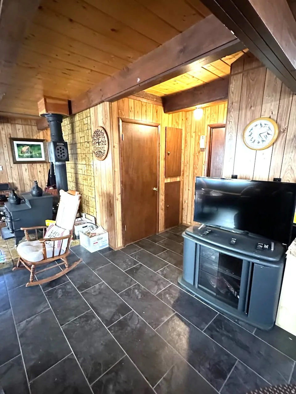 Sitting room featuring wood walls, a wood stove, and a wooden ceiling with exposed beams