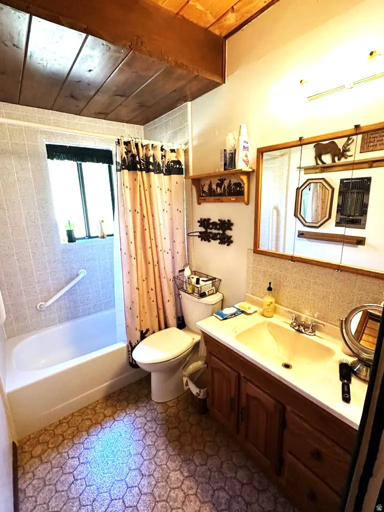 Full bathroom with a wood ceiling with exposed beams, vanity, and shower / bath combo