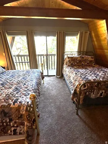 Carpeted bedroom featuring wood ceiling, vaulted ceiling with beams, access to outside, and ceiling fan