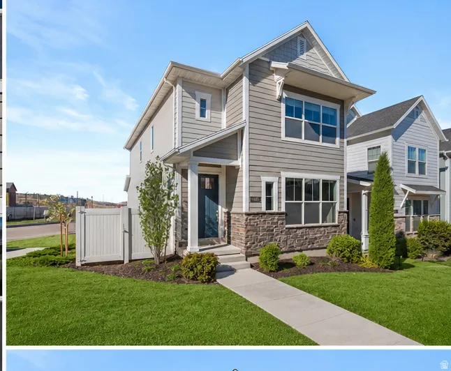 Contemporary two-story exterior featuring a prominent gabled roofline, mixed material siding, stone veneer accents, an inviting covered front entry, and a manicured lawn