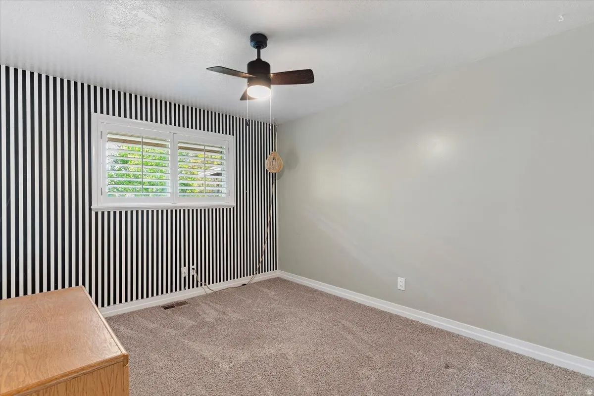 Unfurnished room featuring light carpet, a ceiling fan, a textured ceiling, and wallpapered walls