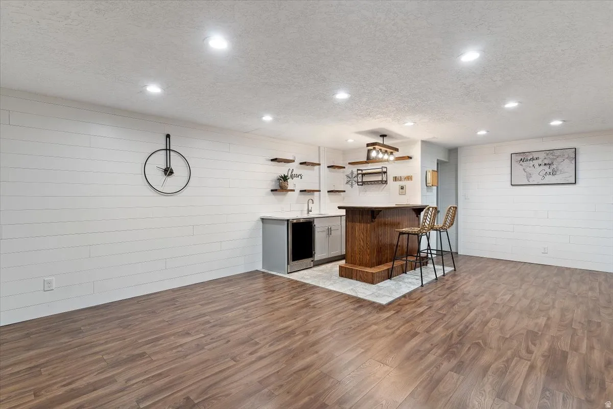 Kitchen featuring open shelves, a breakfast bar area, a textured ceiling, dark wood-style floors, and a peninsula