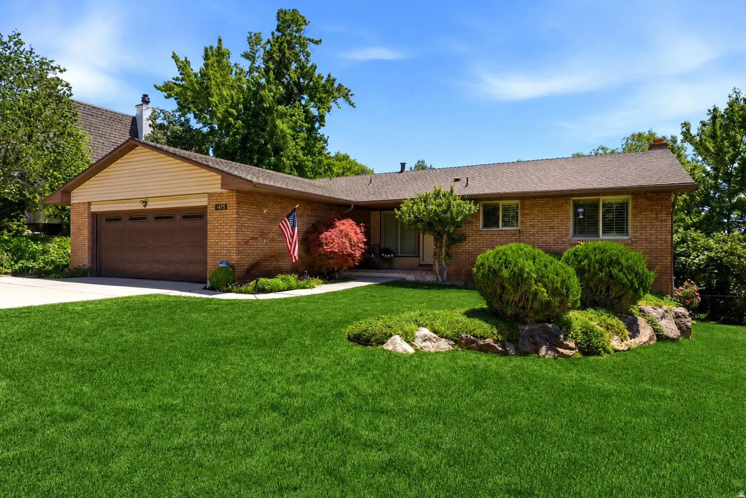 Brick exterior with a brown shingle roof, attached garage with a dark wood-finish door, and a concrete driveway