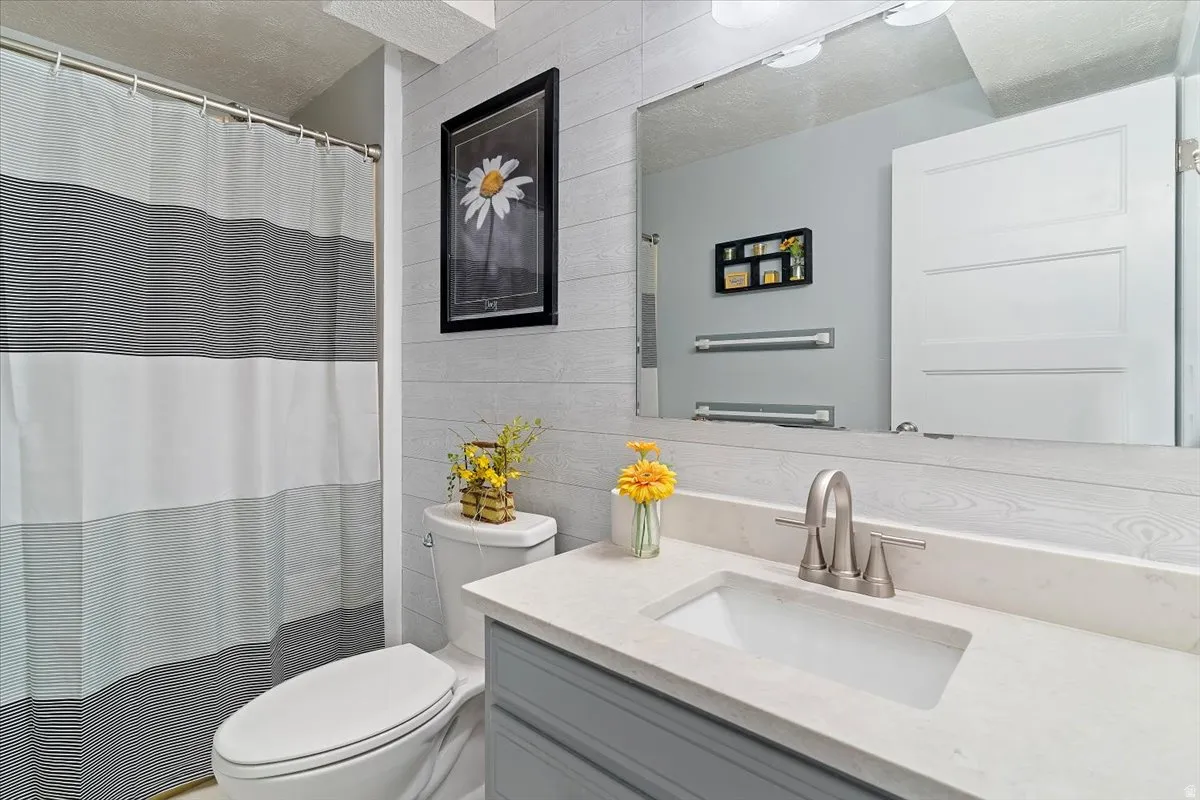 Full bath featuring vanity, a shower with curtain, and a textured ceiling