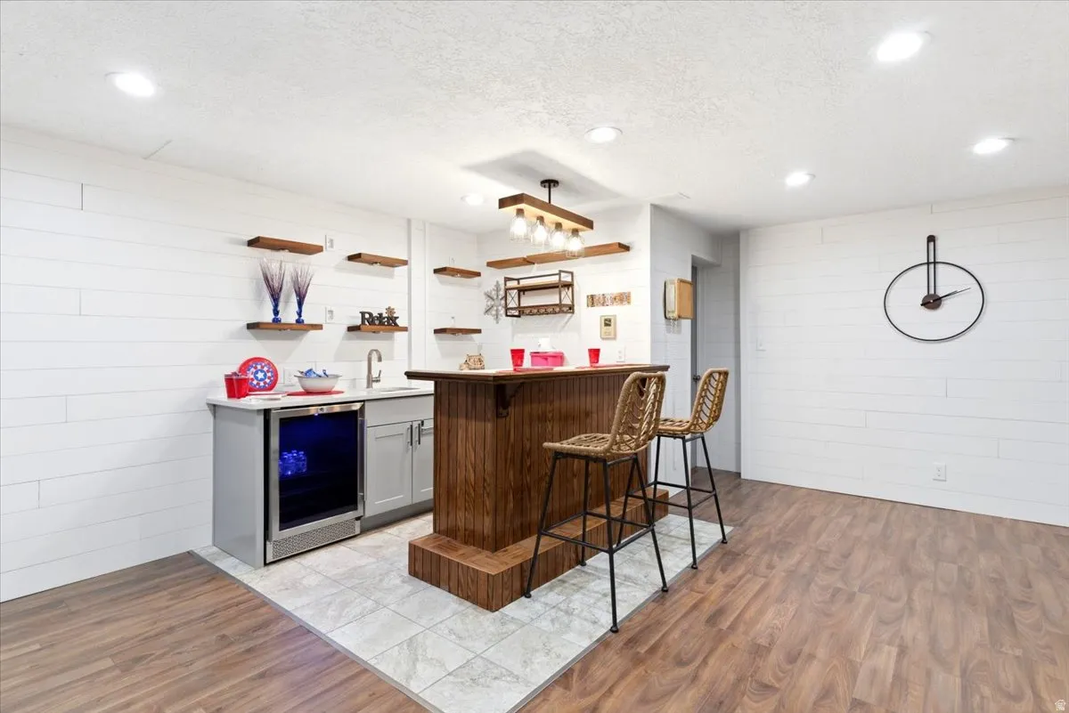 Custom bar area featuring wood-finish flooring, white shiplap walls, recessed lighting, and a built-in beverage cooler
