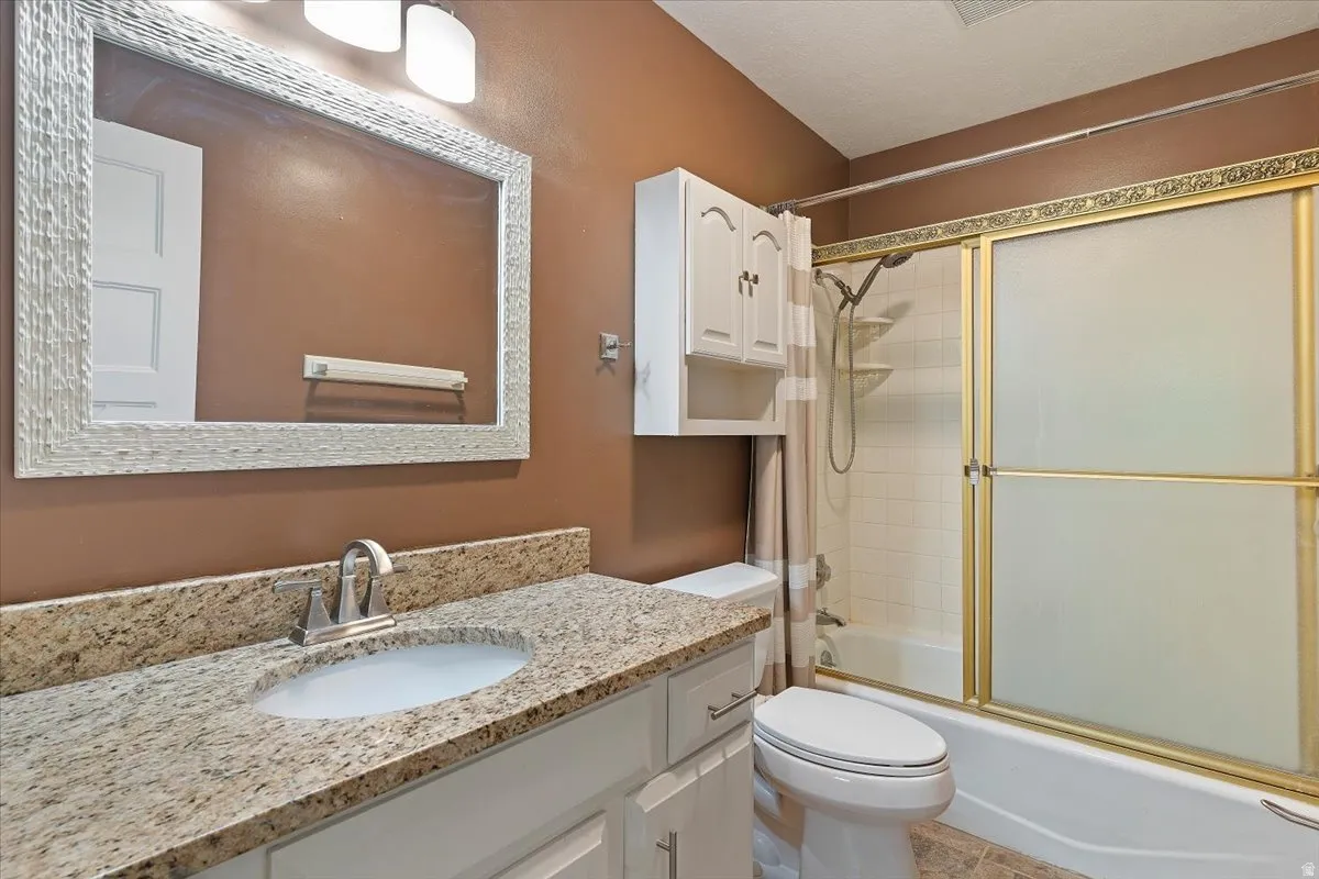 Bathroom with vanity and combined bath / shower with glass door
