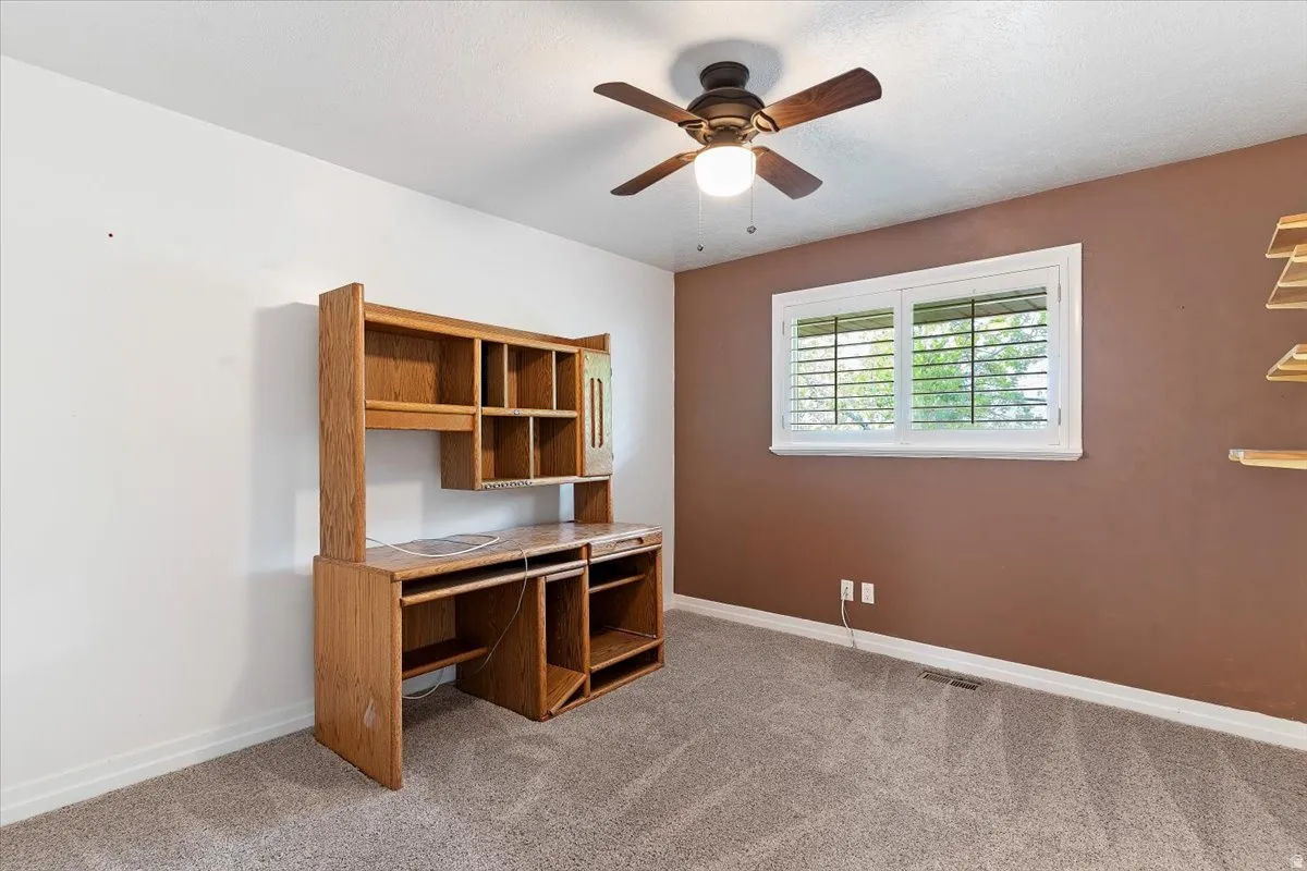 Unfurnished office with light colored carpet and a ceiling fan