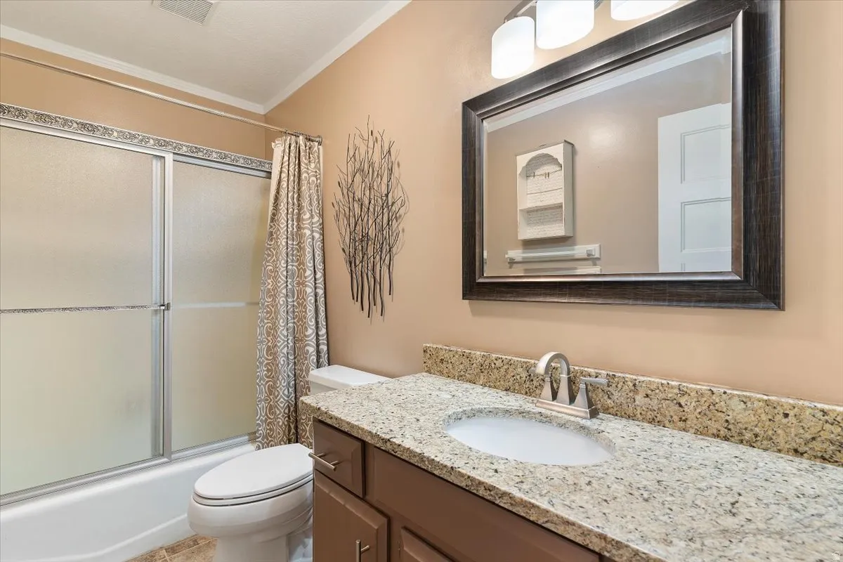 Bathroom featuring vanity, combined bath / shower with glass door, and ornamental molding