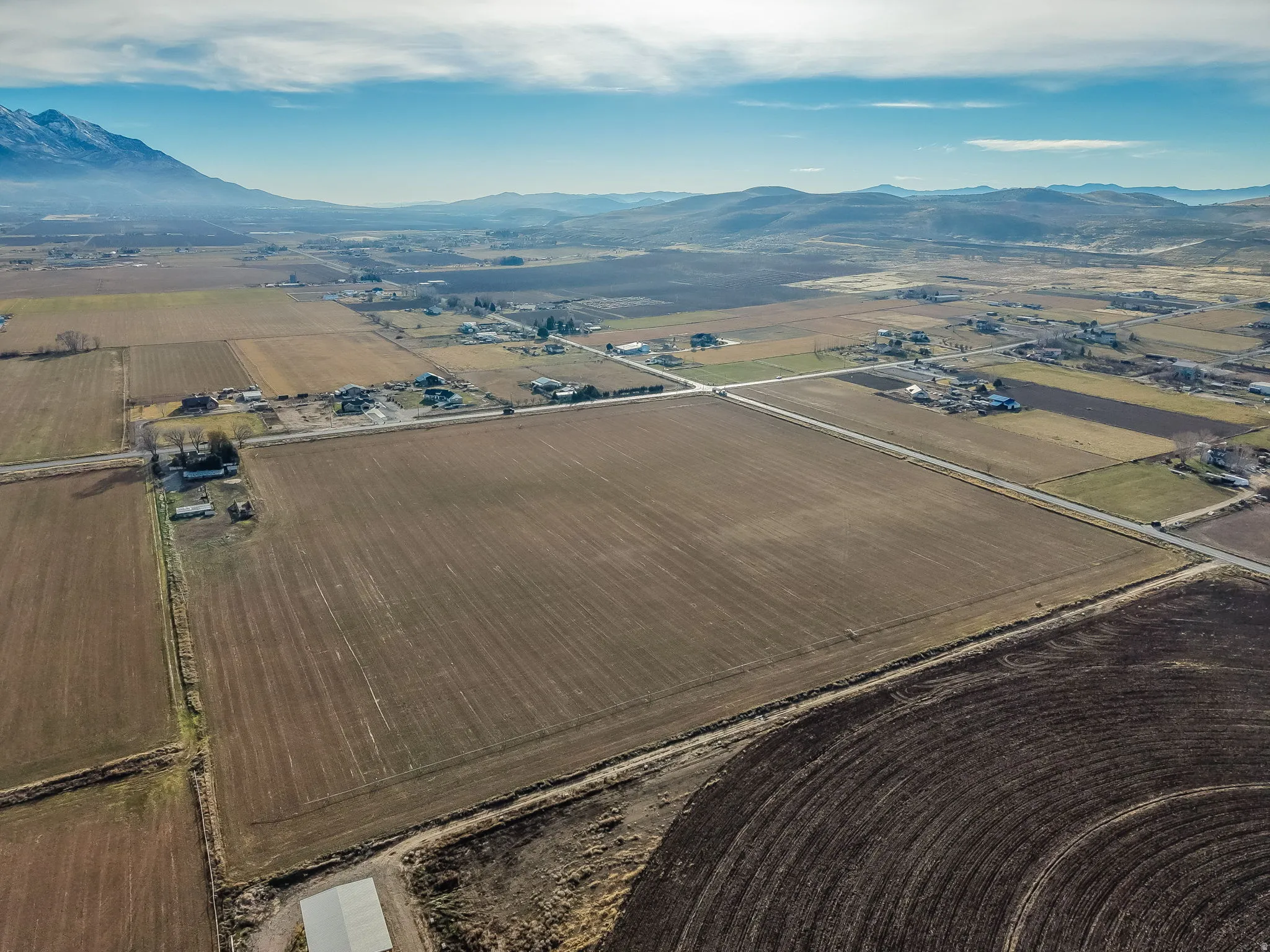 Aerial view of property and surrounding area featuring mountains, rural landscape, and extensive farmland