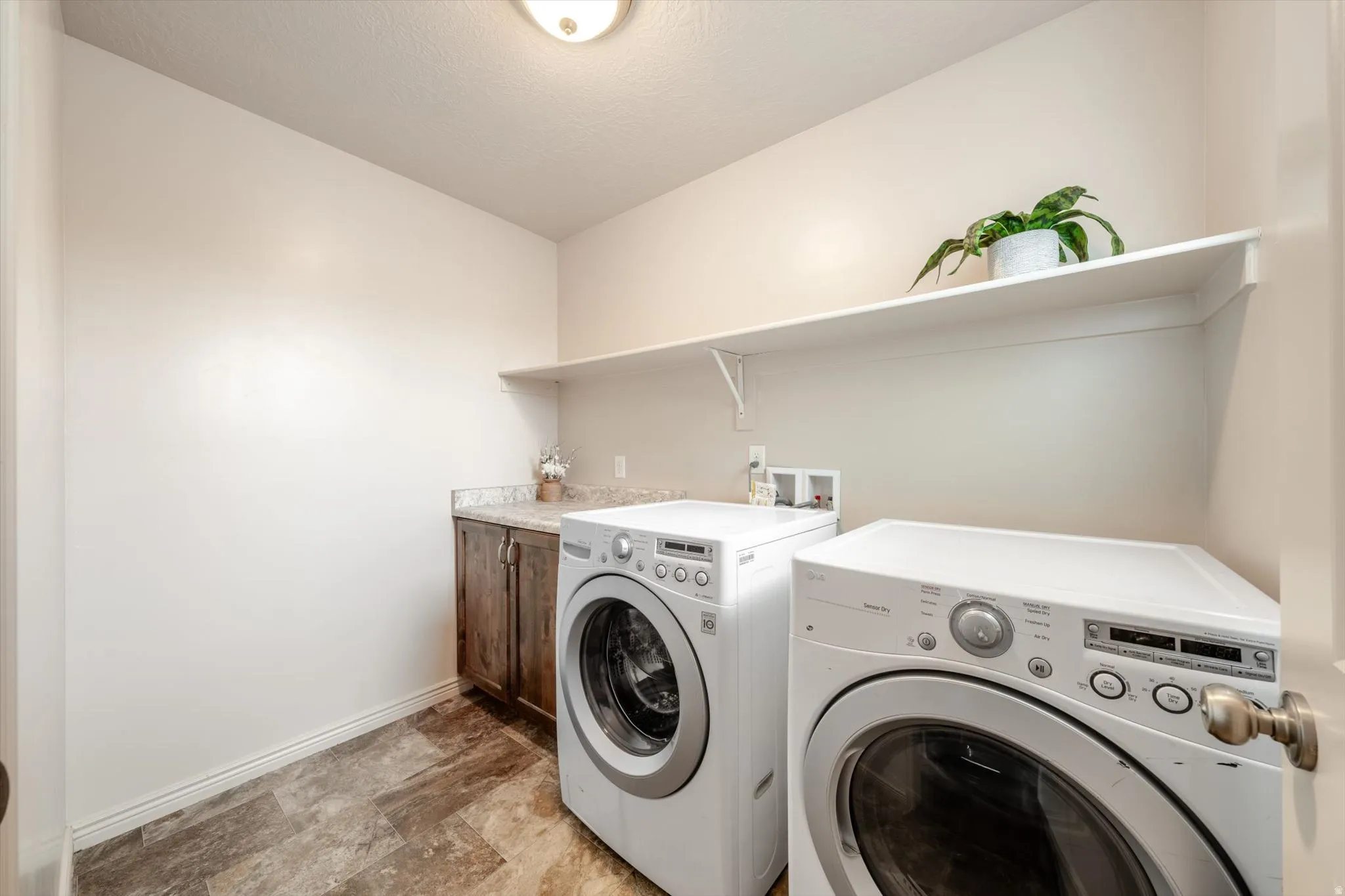 Laundry area featuring stone finish floors and washer and clothes dryer