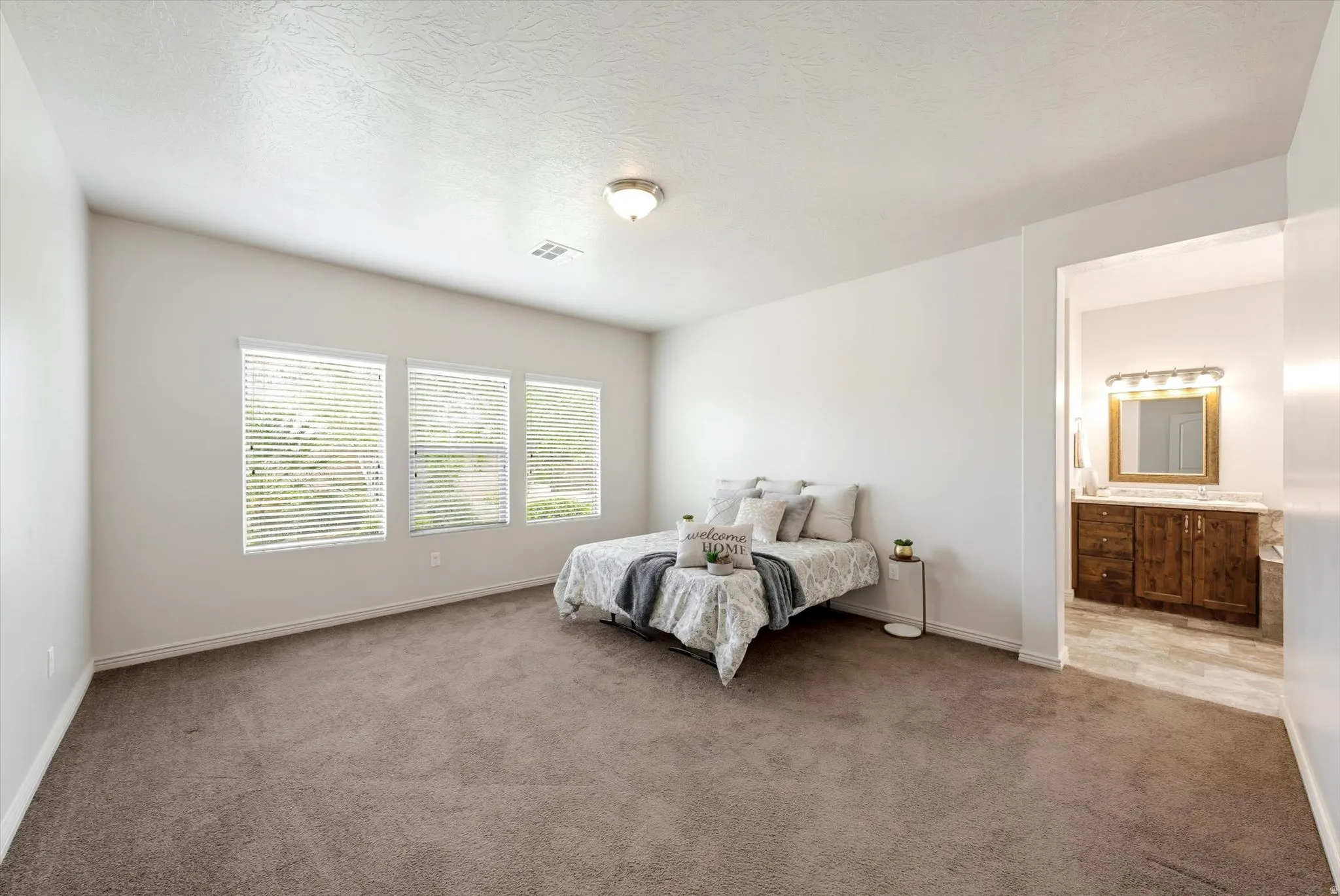 Bedroom featuring light carpet and ensuite bathroom